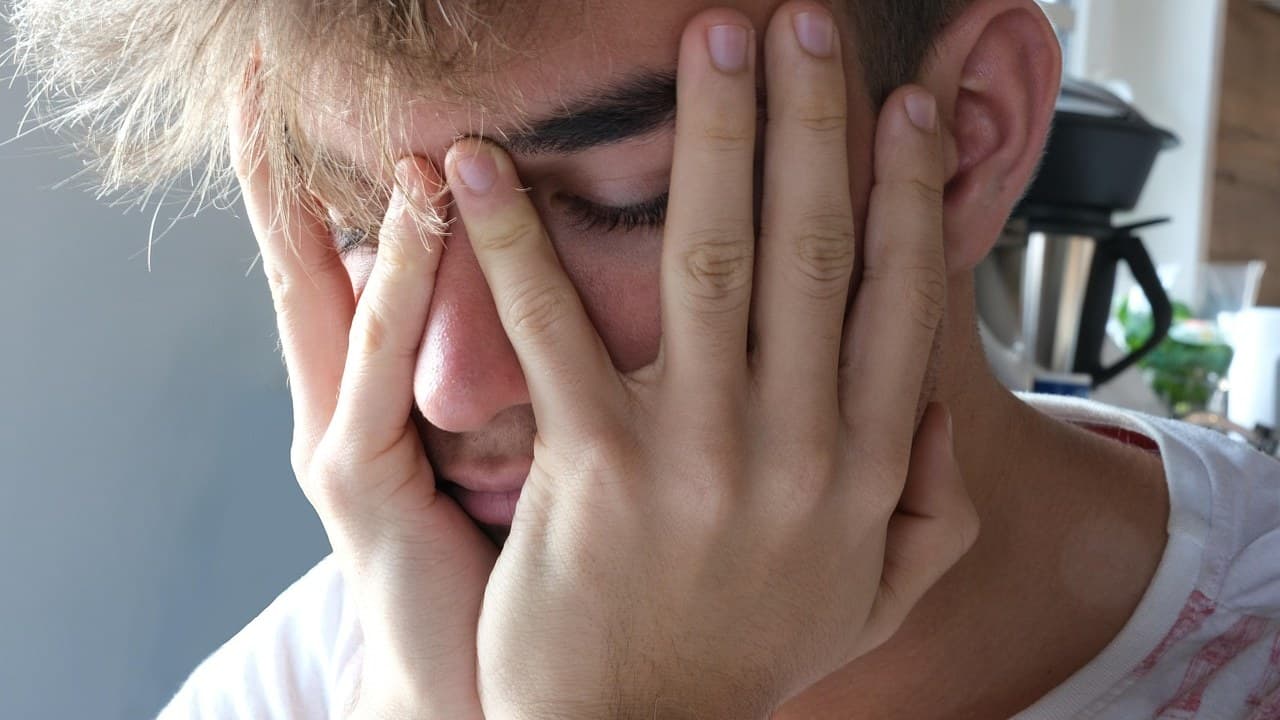 Egy személy eltakarja az arcát, ami az ADHD-val járó érzelemszabályozási nehézségeket tükrözi.