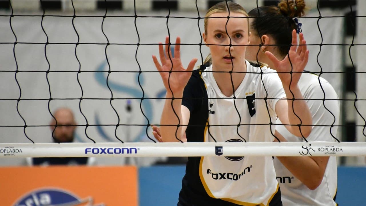 Női röplabdázó a háló mögött, kezeit felemelve, egy MÁV Előre - UTE Extraliga mérkőzésen.
