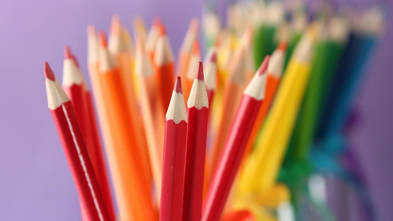 Élesített színes ceruzák, főleg piros és narancssárga, kreativitást és rajzpályázatot sugallva.