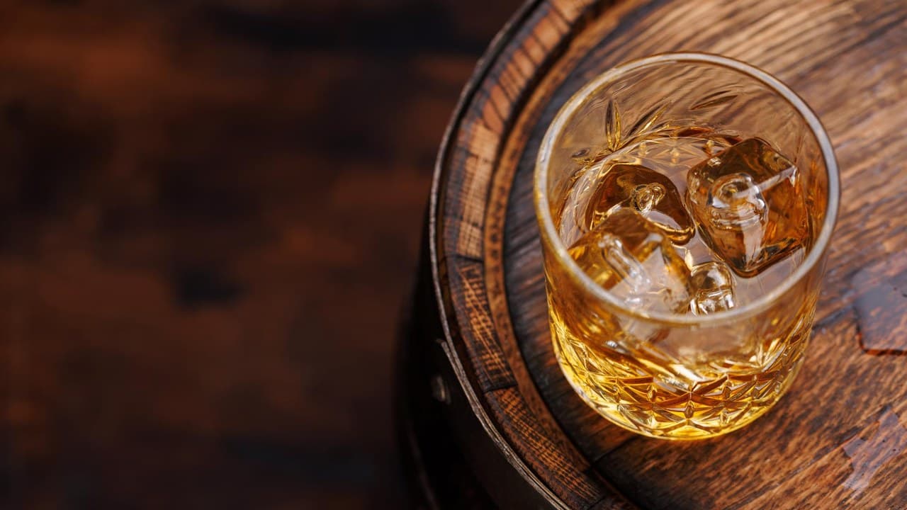 Egy pohár whisky jéggel egy fahordón, utalva az Egyesült Államok whisky túltermelésére és a vámháborúra.